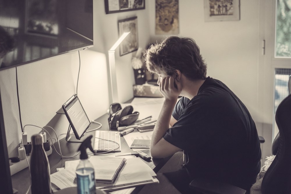 Person at a home-office desk with a tablet, keyboard and notes