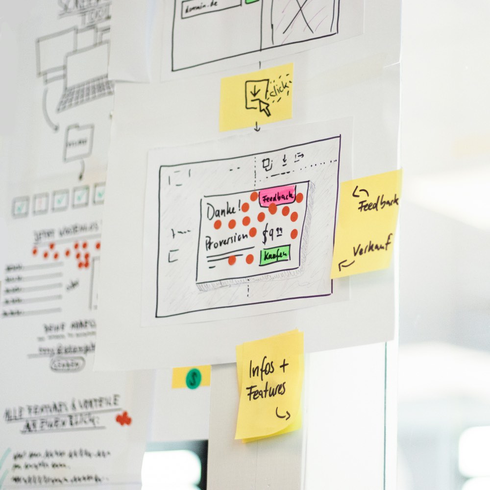 Wireframe sketches and yellow sticky notes on a glass wall